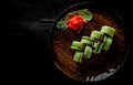 Sushi roll with tuna, cucumber, cream cheese, rice in plate on black wooden table