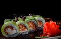 Sushi roll with tuna, cucumber, cream cheese, rice in plate on black wooden table Royalty Free Stock Photo