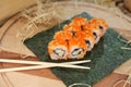 Sushi roll with unagi eel served on nori seaweed sheet with chopsticks near dish