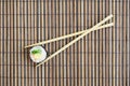 Sushi roll and wooden chopsticks lie on a bamboo straw serwing mat. Traditional Asian food. Top view. Flat lay minimalism shot
