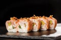 Sushi Rolls with avocado, shrimp, green onion, flamed salmon and Cream Cheese inside and fried onion on top on black slate