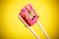 Sushi rolls close-up in wooden sticks on a bright yellow gradient background