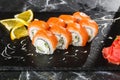 Sushi Rolls with cucumber, avocado, salmon and Cream Cheese inside on black slate isolated on black marble background. Royalty Free Stock Photo