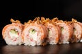 Sushi Rolls with cucumber, shrimp, crab meat, flamed salmon and Cream Cheese inside and fried onion on top on black