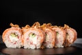 Sushi Rolls with cucumber, shrimp, crab meat, flamed salmon and Cream Cheese inside and fried onion on top on black