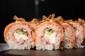 Sushi Rolls with cucumber, shrimp, crab meat, flamed salmon and Cream Cheese inside and fried onion on top on black