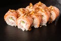 Sushi Rolls with cucumber, shrimp, crab meat, flamed salmon and Cream Cheese inside and fried onion on top on black