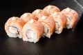 Sushi Rolls with flamed salmon, shrimp, crab meat and Cream Cheese inside on black slate isolated. Philadelphia roll sushi with Royalty Free Stock Photo