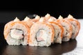 Sushi Rolls with flamed salmon, shrimp, crab meat and Cream Cheese inside on black slate isolated. Philadelphia roll sushi with Royalty Free Stock Photo