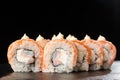 Sushi Rolls with flamed salmon, shrimp, crab meat and Cream Cheese inside on black slate isolated. Philadelphia roll sushi with Royalty Free Stock Photo