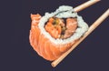 Sushi rolls holding by chopsticks. A traditional dish of Japanese cuisine. Royalty Free Stock Photo