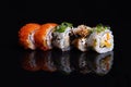 Sushi rolls isolated on black background, food reflection in glass, japanese food, set with salmon, vegetables, flying fish