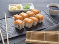 Sushi rolls philadelphia on a black textured plate stand on a gray background. wasabi ginger and sauce chopsticks. Rolls with Royalty Free Stock Photo