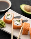 Sushi rolls Philadelphia with salmon and avocado. Roll ready to eat on cutting board with wasabi and soy sauce. Asian or Royalty Free Stock Photo