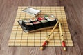 Sushi rolls on a plate on bamboo brown straw mat with chopsticks close up Royalty Free Stock Photo