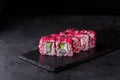 Sushi rolls with rice, nori, cremette cheese, cucumber, masago, sesame and scallop on a black slate Royalty Free Stock Photo