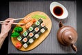 Sushi rolls, sauce and woman hand holding chopsticks on a grey background. Top view. Flat lay. Royalty Free Stock Photo