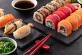 Sushi rolls set, nigiri sushi and soy sauce on a black textured background and chopsticks on the side. Royalty Free Stock Photo