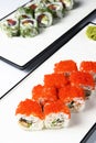 Sushi rolls set with red caviar and cream cheese served on a white plate over white background. Royalty Free Stock Photo