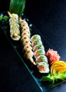 Sushi rolls set served on glass plate on dark background