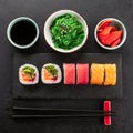 Sushi rolls set, soy sauce, seaweed salad and chopsticks from below on black slate board Royalty Free Stock Photo