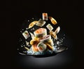 Sushi, rolls and soy sauce levitate over a plate on a black background Royalty Free Stock Photo