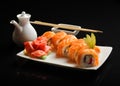 Sushi and rolls on a square plate with wasabi, soy sauce and chopsticks on a black background Royalty Free Stock Photo