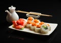 Sushi and rolls on a square plate with wasabi, soy sauce and chopsticks on a black background Royalty Free Stock Photo