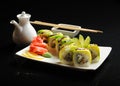 Sushi and rolls on a square plate with wasabi, soy sauce and chopsticks on a black background Royalty Free Stock Photo