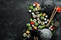 Sushi rolls and teapot with tea on black stone background. Royalty Free Stock Photo