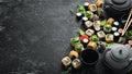 Sushi rolls and teapot with tea on black stone background. Royalty Free Stock Photo