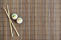 Sushi rolls and wooden chopsticks lie on a bamboo straw serwing mat. Traditional Asian food. Top view. Flat lay minimalism shot