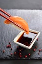 Sushi sake in chopsticks dipped in soy sauce