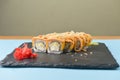 Sushi set California or Philadelphia served on a black board over pastel blue background