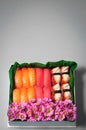 Sushi set with flowers in gift box on grey background. Creative chocolate candy box. Date, Valentines Day, Mother`s day