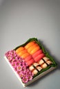 Sushi set with flowers in gift box on grey background. Creative chocolate candy box. Date, Valentines Day, Mother`s day