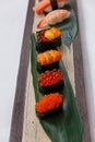 Sushi Set Include Tobiko, Ikura, Sea Urchin and Ikura, Urchin and Quail Egg Yolk Served on Leaf on Stone Plate