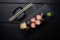 Sushi set with salmon served on black clay plate with soy sauce and chopsticks, top view. Delicious traditional Japanese food with Royalty Free Stock Photo