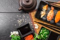 Sushi set sashimi and sushi rolls and white flowers on dark background