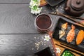 Sushi set sashimi and sushi rolls and white flowers on dark background