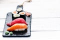 Sushi set served on a black slate. Sushi rolls and sashimi on a wooden white table. Seafood. Raw fish. White background. Wasabi. Royalty Free Stock Photo