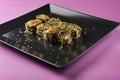 Sushi set served on a black square plate over bright pink background. Traditional Japanese cuisine, sushi rolls close up Royalty Free Stock Photo