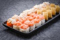 Sushi set served on dark background. Baked maki roll, Philadelphia maki, tempura maki with salmon, cream cheese, avocado and prawn