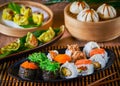 Sushi Set uramaki, gunkan, Gyozas dumplings and wakame salad in ceramic plates with soy sauce and chopsticks on bamboo mat. Copy Royalty Free Stock Photo