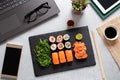 Sushi takeaway at work desk with laptop overhead. Eating sushi for lunch break at office, lunch meal at work, top view Royalty Free Stock Photo