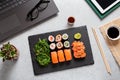 Sushi takeaway at work desk with laptop overhead. Eating sushi for lunch break at office, lunch meal at work, top view Royalty Free Stock Photo