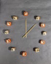 Sushi time in the form of a wall clock on a gray or grey stone background. Creative advert concept, advertisement. Royalty Free Stock Photo