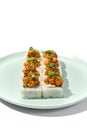 Sushi topped salmon tartare and micro greens Maki sushi with salmon in teriyaki sauce on ceramic plate. Salmon maki top tartare
