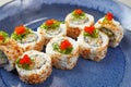 Sushi Uramaki with fish, green algae, rolls sprinkled with red caviar, with spices, in a blue plate