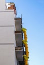 Suspended sections of yellow plastic garbage chute on a facade of building under construction against clear blue sky Royalty Free Stock Photo